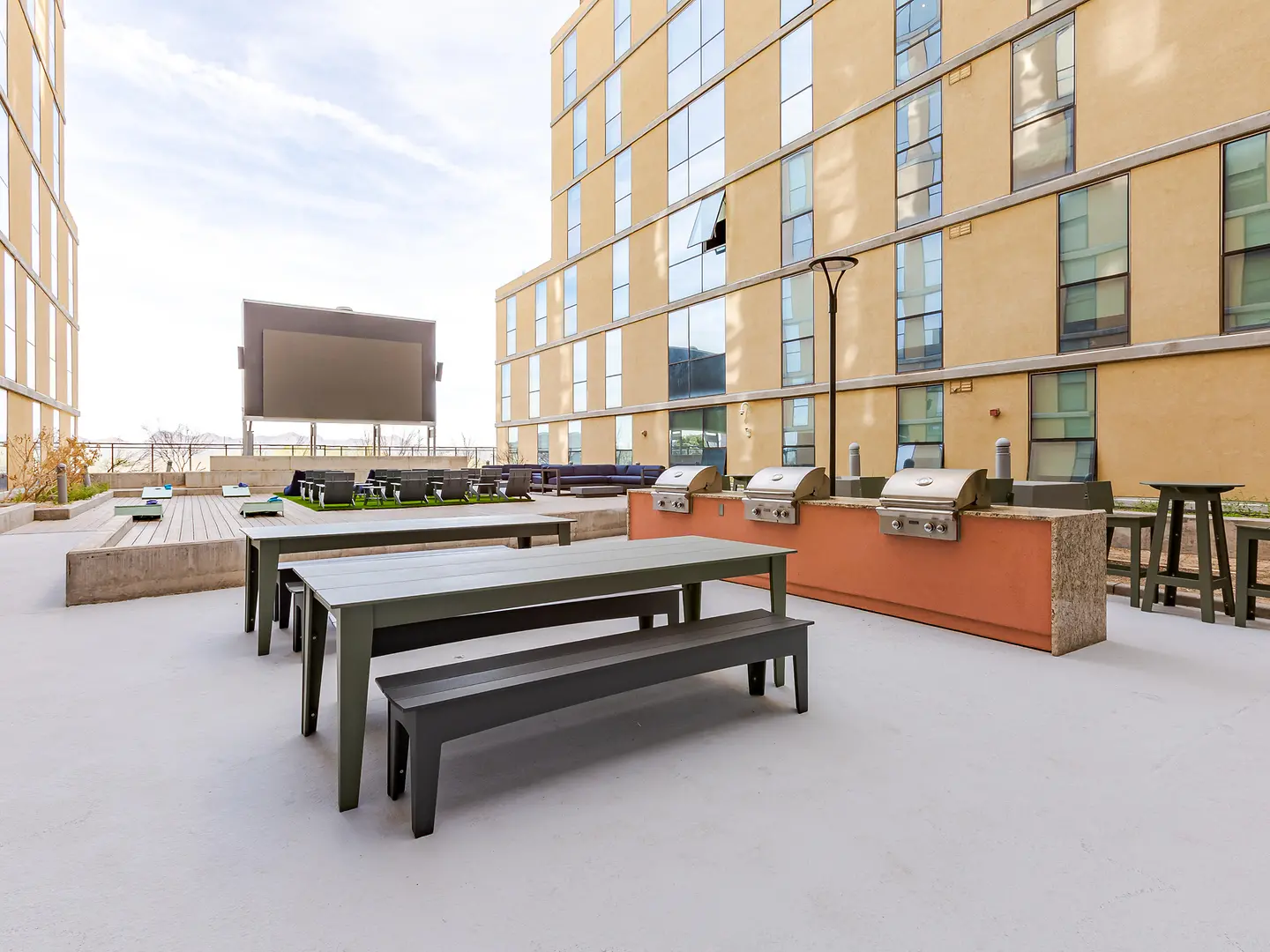 Terrace with barbecue grills, picnic tables and a large screen.