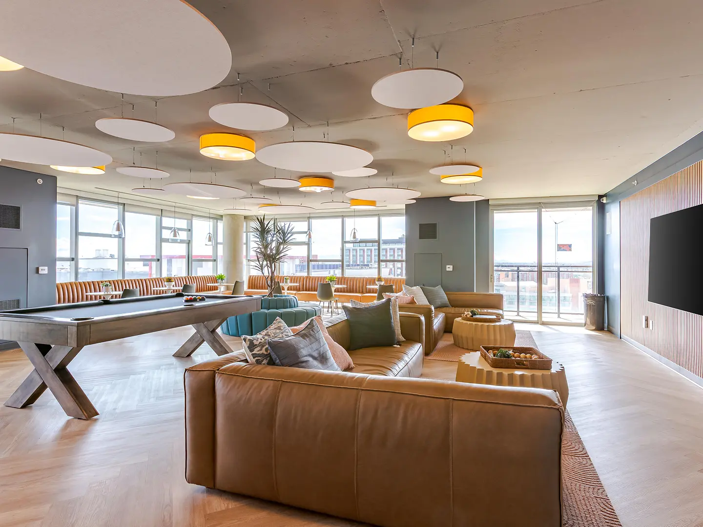 Community lounge with a pool table, sofas and window seating.